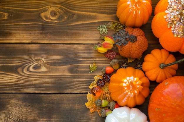 Orange and white pumpkins and jack lantern with his eyes and mouth cut out on a wooden table with yellow autumn maple leaves berries Autumn mood halloween home decor