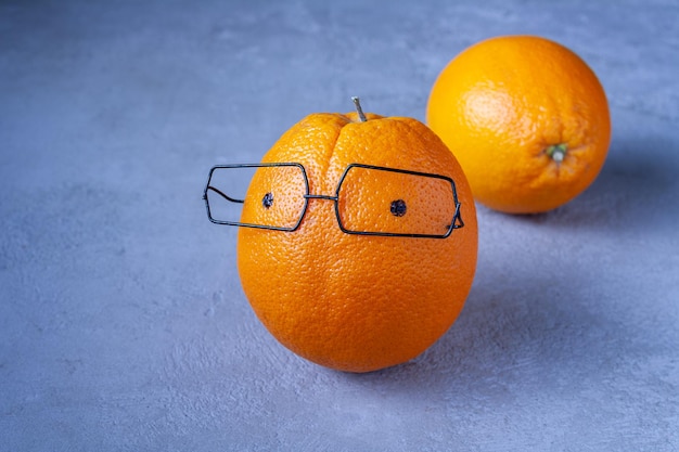 Orange with glasses on a blue background copy space