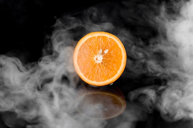 Orange with smoke on black surface