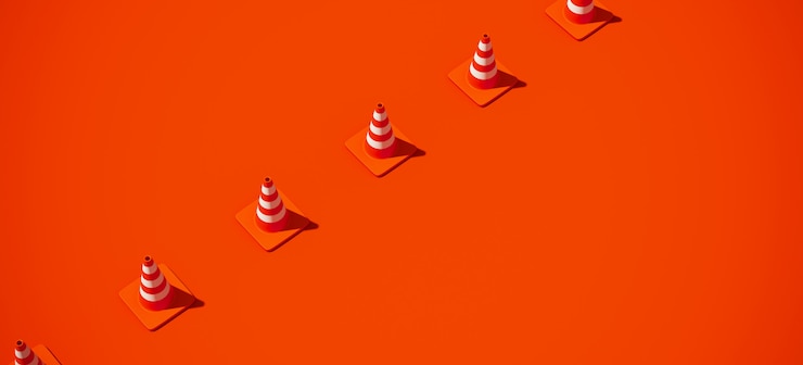 オレンジ色の背景に白のストライプトラフィックコーンとオレンジ