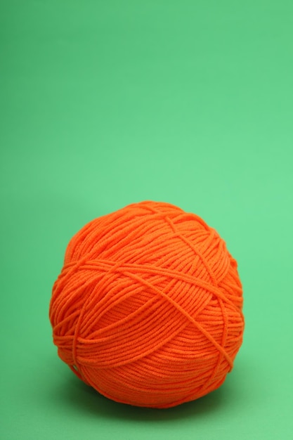 orange woolen skein on green background. High quality photo