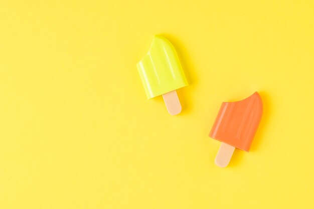 Orange and yellow popsicle on a yellow background. A popular summer snack.