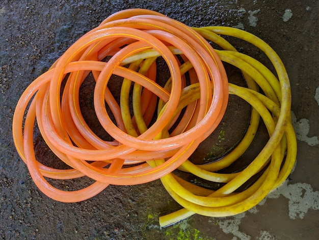 Orange and yellow rubber water hose on the ground