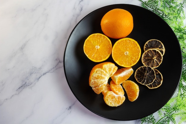 Photo oranges on a black plate  top view