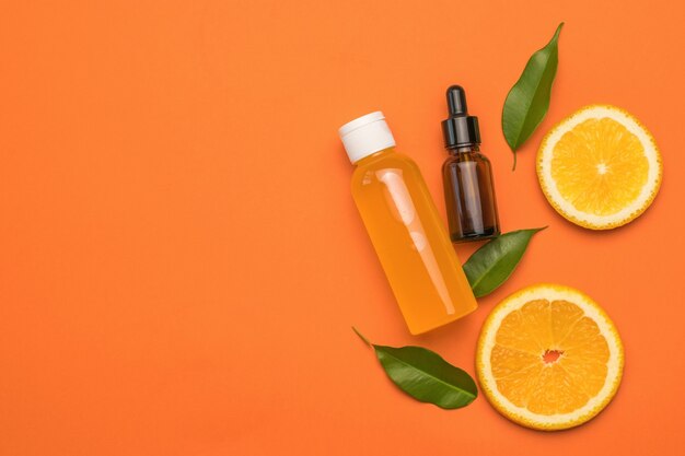 Oranges, a bottle of juice and a medical bottle on an orange background.