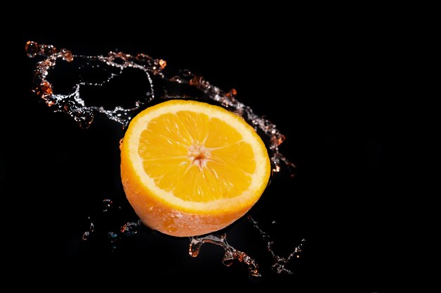 Oranges falling into water splashing on black background and good for health.