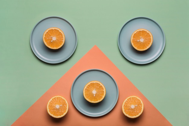 Oranges on the flat plates on the color green and orange background. Concept of healthy nutrition and vitamins.