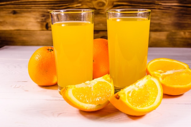 Oranges and glasses with orange juice on a wooden table