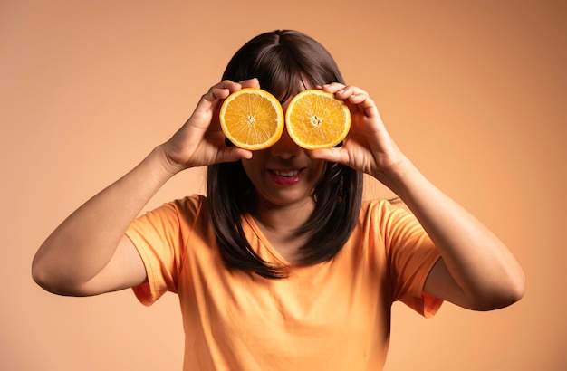 Foto arance messe negli occhi di una donna su sfondo arancione