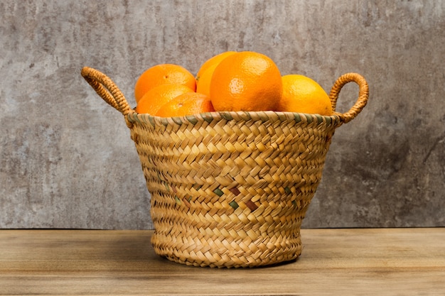 Oranges in a wicker basket on a wooden table