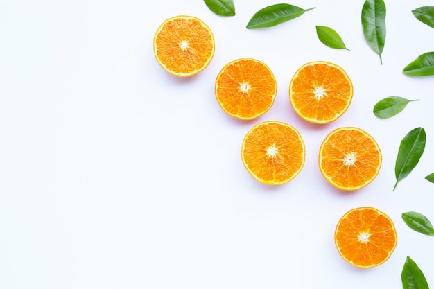 Апельсины с листьями на белой стене.