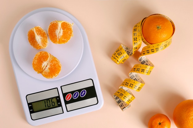 Апельсины с рулеткой и цифровыми кухонными весами.