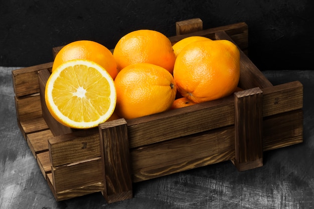 Oranges in a wooden box on a black background