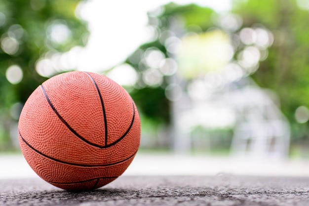 Oranje bal voor spelbasketbal op een vloer in basketbalhof bij het park