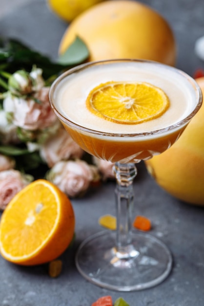 Oranje cocktail met een schijfje sinaasappel op een zwarte betonnen ondergrond. Zomercocktailconcept met decor