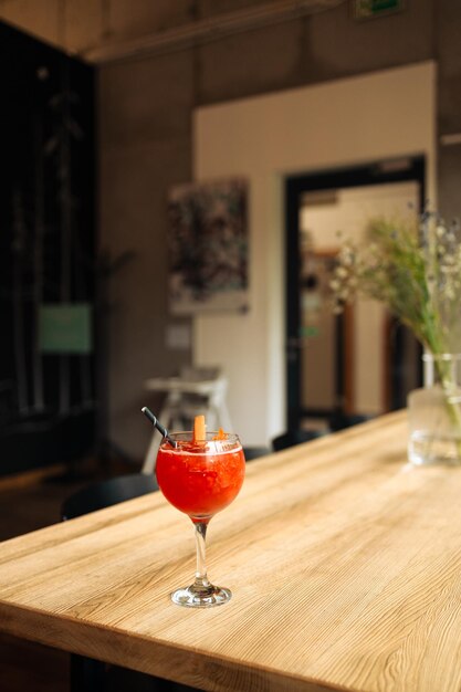 Oranje cocktail met grapefruit ijs en rozemarijn in een doorzichtig glas op een houten tafel in stijl