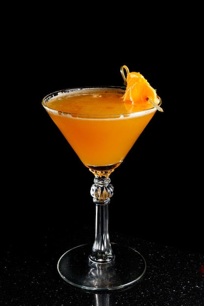 Oranje cocktail met mandarijnen in martini glas op zwarte achtergrond