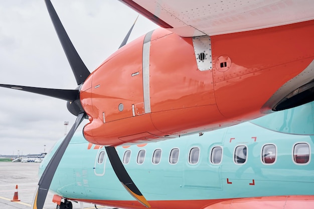 Oranje en blauw gekleurde Turboprop-vliegtuigen die overdag op de startbaan zijn geparkeerd