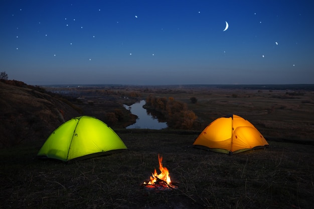 Oranje en groene tent bij de rivier 's nachts