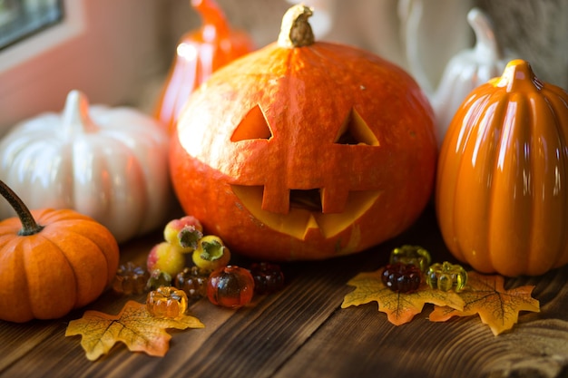 Oranje en witte pompoenen en jack lantaarn met zijn ogen en mond uitgesneden op een houten tafel met gele herfst esdoorn bladeren bessen herfst stemming halloween home decor