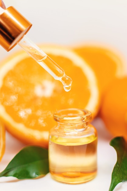Oranje etherische olie in een fles en sinaasappelen