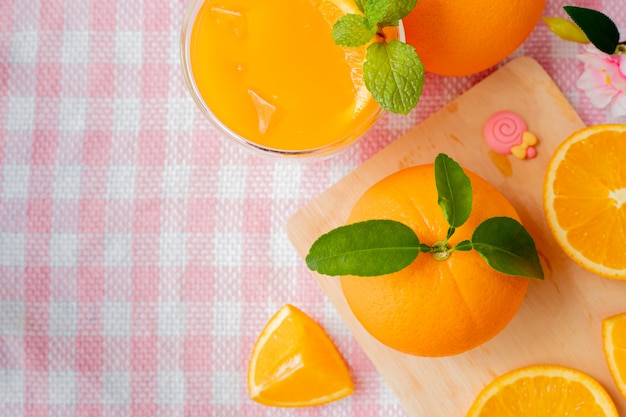 Oranje fruit en glas koud jus d'orange op roze tafelkleed.