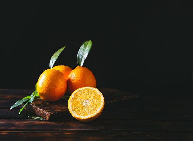 Oranje fruit zowel geheel als gesneden op een rustieke houten tafel