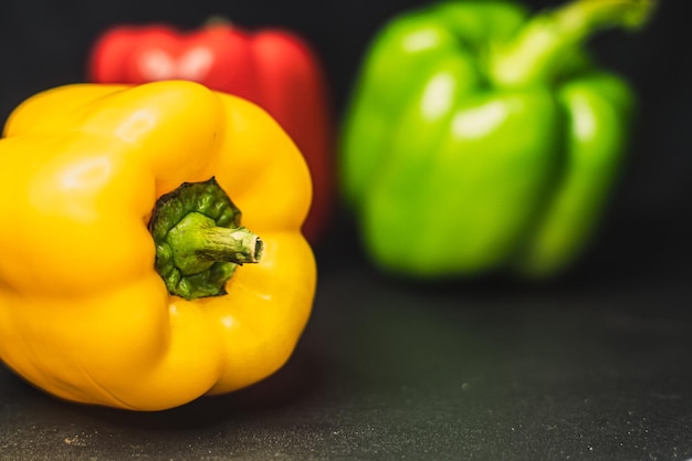 Foto oranje gele rode paprika groene paprika's op donkere achtergrond