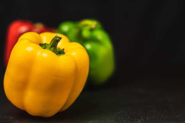 Oranje gele rode paprika groene paprika's op donkere achtergrond