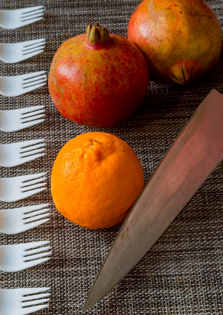 Oranje granaatappelvruchten geplaatst op een tafelmat met fruitvork en mes