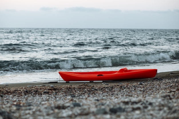 Oranje kajak met een roeispaan aan zee