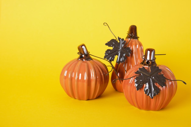 Oranje keramische Halloween-pompoenen met bruine metalen bladeren op geel