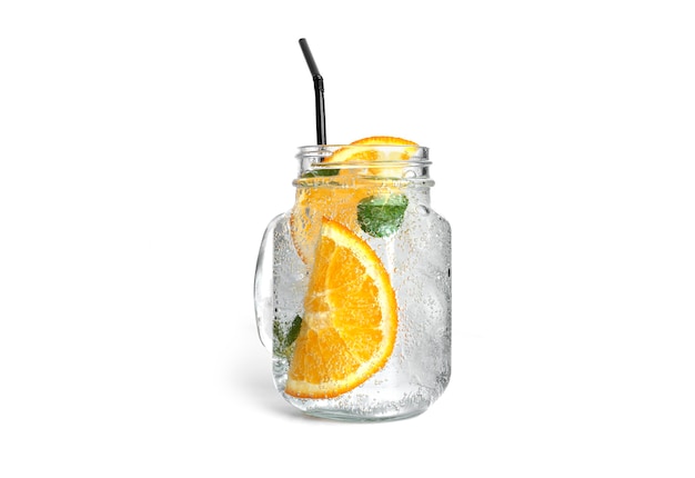 Oranje limonade met munt en ijs in een duidelijke geïsoleerde metselaarkruik