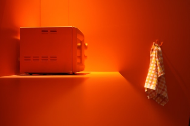 Oranje magnetron bij oranje keuken met witte handdoek. verwarmingsenergie in de magnetron.