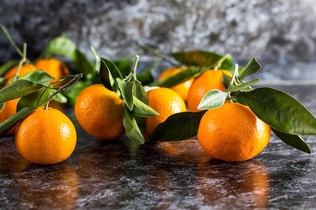 Oranje mandarijnen met groene bladeren op donkere achtergrond