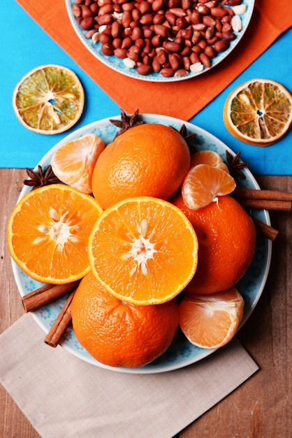 Oranje mandarijnen pinda's en kaneel stokjes op blauwe houten tafel top view