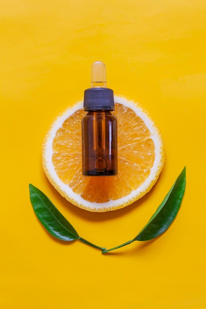 Foto oranje organische aromatische olie in een glazen fles met een pipet op een achtergrond van verse sinaasappelschijven
