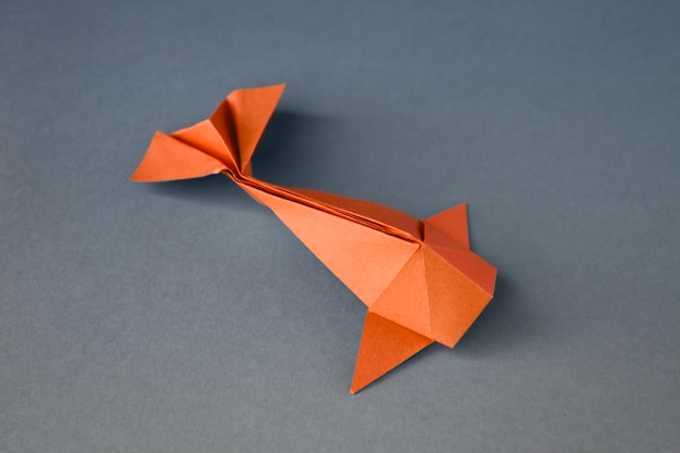 Oranje papieren vis origami geïsoleerd op een grijze achtergrond