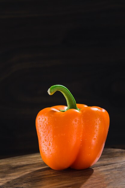 Oranje paprika op een donkere houten bord