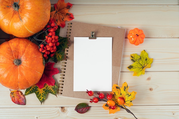 Oranje pompoenen esdoornblad bessen en blanco papier