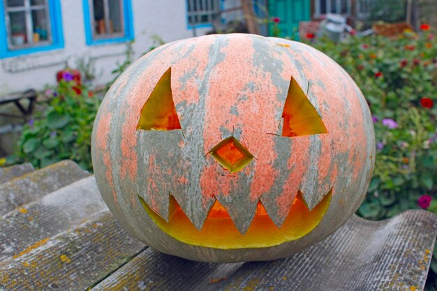 Oranje pumpking met gesneden gezicht is klaar voor Halloween op de achtergrond van een landelijk huis Halloween in het dorp Pompoensymbool van Halloween