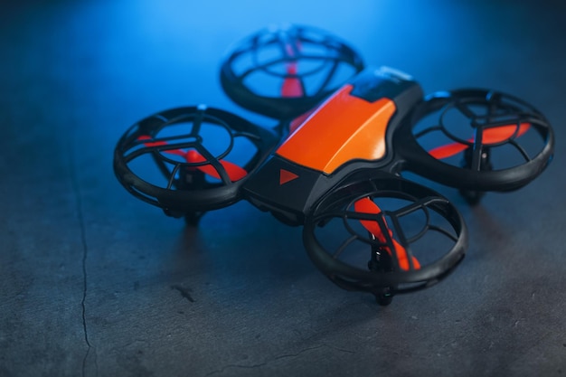 Oranje quadcopter mini spy drone op een donkere achtergrond met blauwe achtergrondverlichting