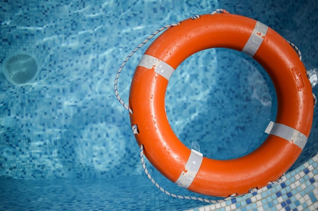 oranje reddingsboei in het zwembad oranje reddingsboei op een achtergrond van water Zomervakantie concept