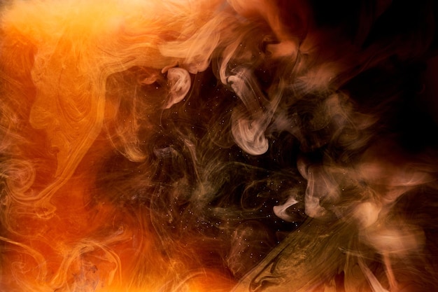 Foto oranje rook op zwarte inktachtergrond, kleurrijke mist, abstracte wervelende oceaanzee, acrylverfpigment onder water