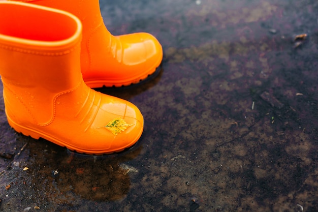 Oranje rubberlaarzen die zich in een vulklei bevinden