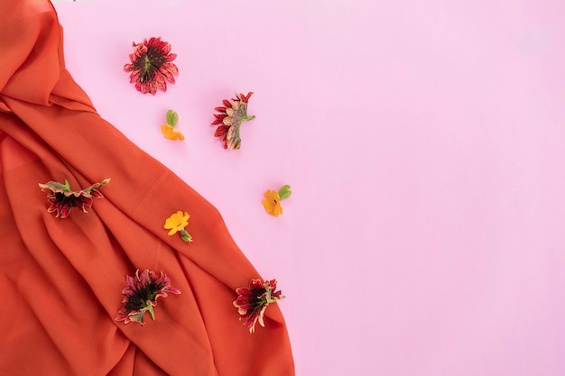 Oranje sjaal, rode bladeren en gele bloemen geïsoleerd op roze achtergrond, minimaal concept idee.