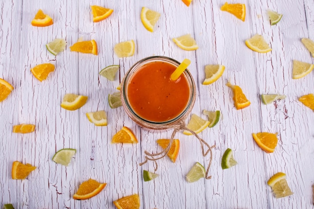 Oranje smoothie staat op witte tafel met veel kleine stukjes