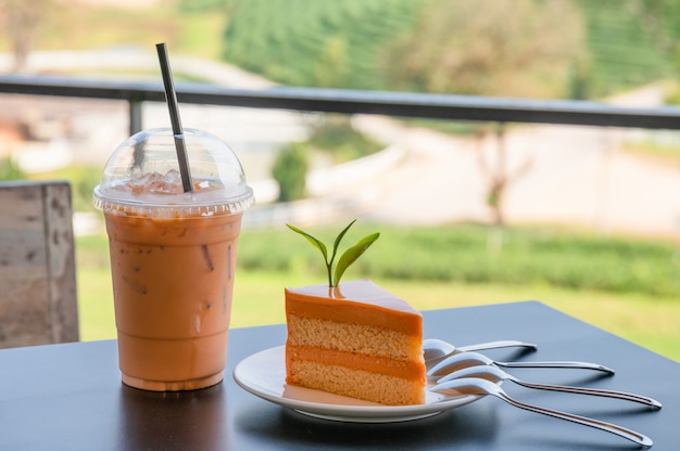 Oranje thaise theekaastaart met drank van de ijs de thaise thee op houten lijst in aanplanting