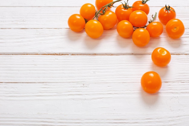 Oranje tomaten kers op witte houten achtergrond