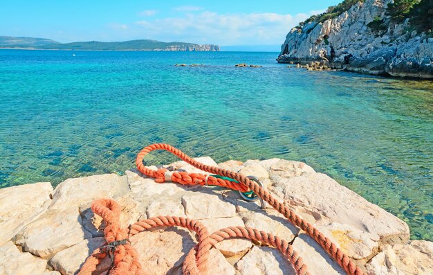 Oranje touw op witte rotsen in Cala Dragunara Sardinië